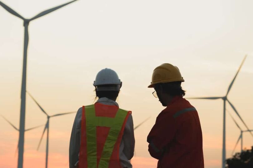 Two workers discuss renewable energy projects at a wind farm during sunset, showcasing dedication to sustainable solutions. What the situation in the Middle East means for our energy and generation